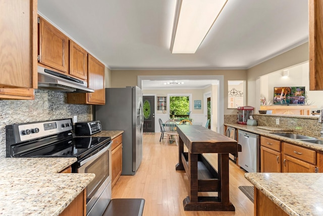 kitchen with sink, light hardwood / wood-style flooring, decorative backsplash, light stone countertops, and appliances with stainless steel finishes