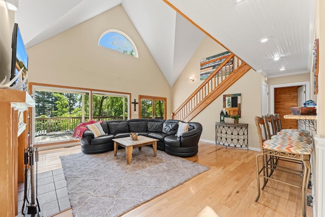 living room with crown molding, light hardwood / wood-style flooring, and a high ceiling