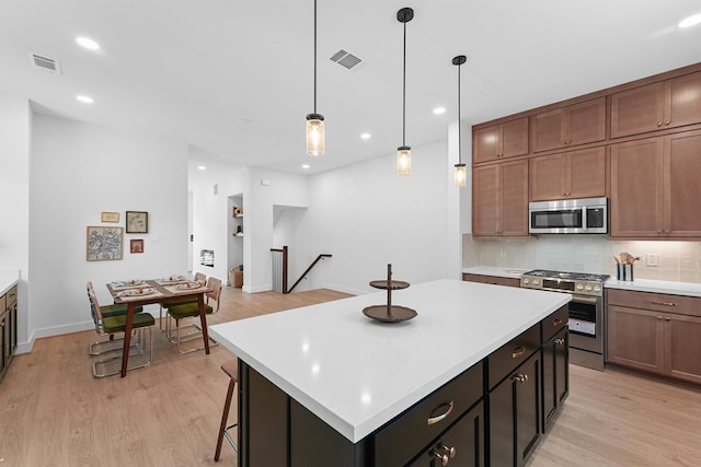 kitchen with pendant lighting, light wood-type flooring, tasteful backsplash, a kitchen island, and stainless steel appliances