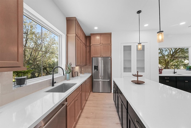 kitchen featuring decorative light fixtures, sink, plenty of natural light, and stainless steel appliances