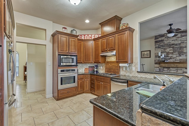 kitchen featuring sink, stainless steel appliances, backsplash, dark stone countertops, and light tile patterned floors