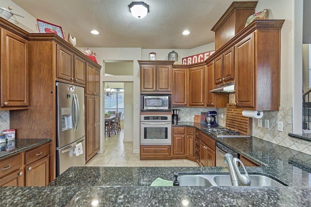 kitchen with stainless steel appliances, tasteful backsplash, dark stone counters, and sink