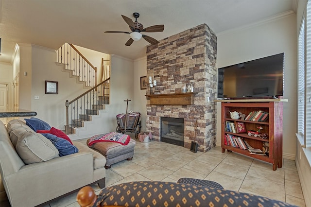 tiled living room featuring a stone fireplace, ceiling fan, and ornamental molding