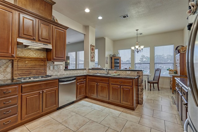 kitchen featuring pendant lighting, backsplash, stainless steel appliances, and a notable chandelier