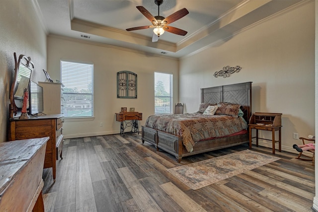 bedroom with dark wood-type flooring, a raised ceiling, ceiling fan, and crown molding