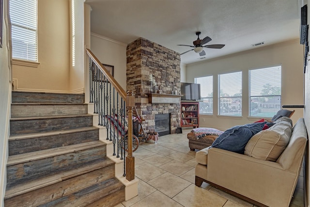 tiled living room featuring ceiling fan, a fireplace, and ornamental molding