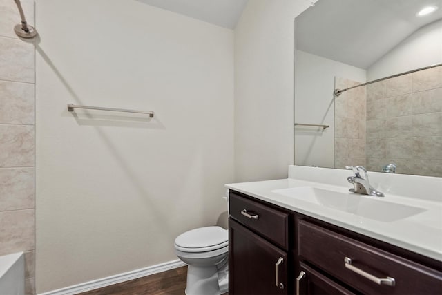 full bathroom featuring hardwood / wood-style floors, vanity, lofted ceiling, tiled shower / bath combo, and toilet