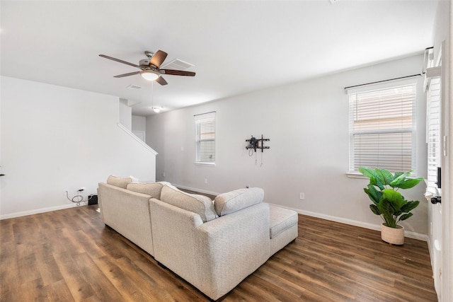 living room featuring ceiling fan, dark wood-type flooring, and a healthy amount of sunlight