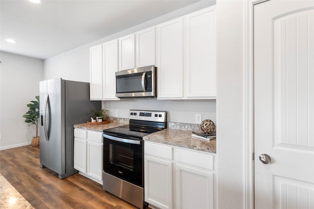 kitchen with white cabinets, appliances with stainless steel finishes, dark hardwood / wood-style floors, and light stone counters