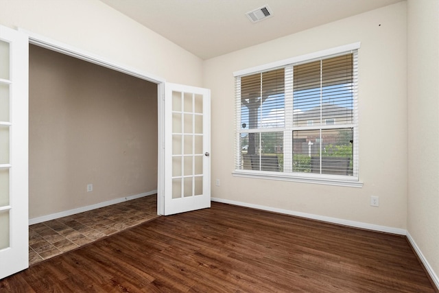 empty room with dark hardwood / wood-style flooring and french doors