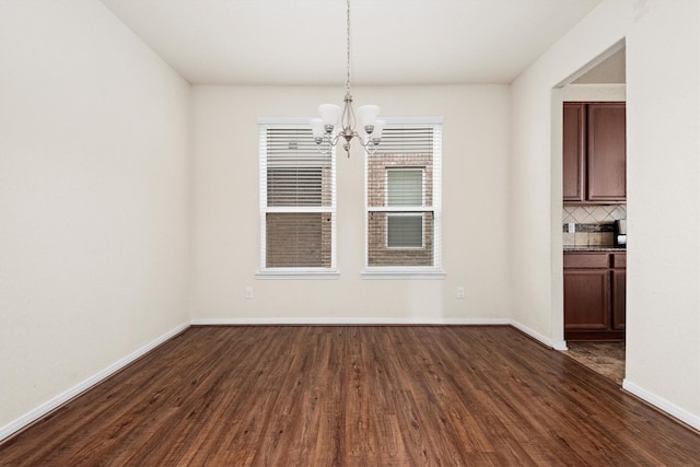 unfurnished dining area with dark wood-type flooring and a notable chandelier