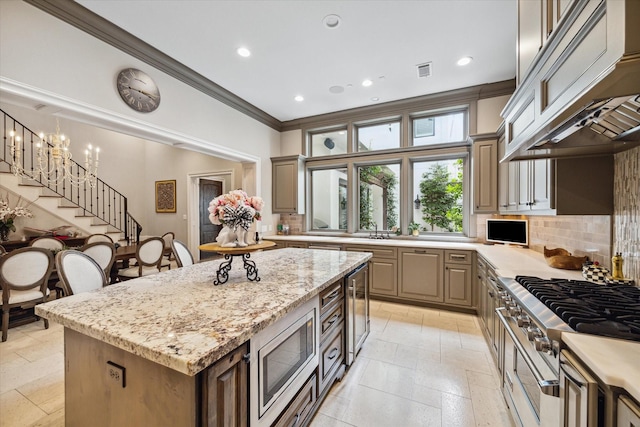 kitchen featuring stainless steel microwave, light stone counters, stovetop, decorative backsplash, and a kitchen island