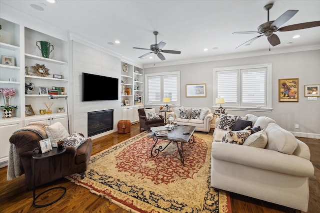 living room with hardwood / wood-style floors, built in features, ornamental molding, and a tiled fireplace