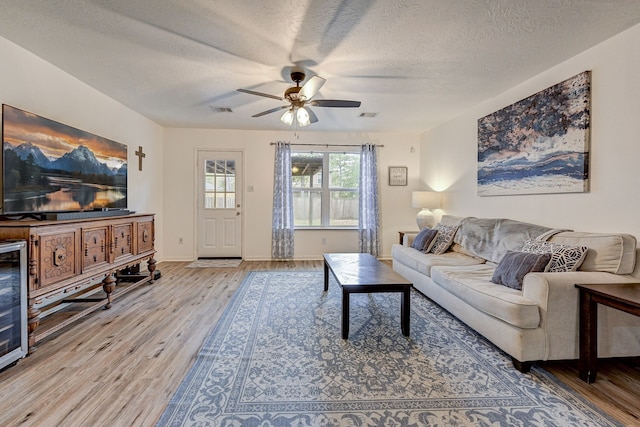 living room featuring hardwood / wood-style flooring, ceiling fan, and a textured ceiling