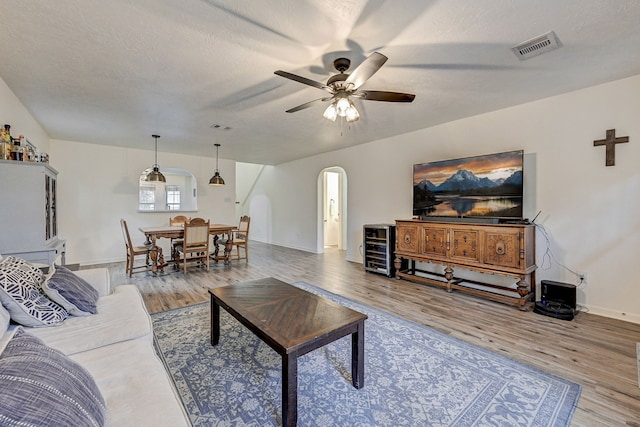 living room with hardwood / wood-style floors, a textured ceiling, and ceiling fan