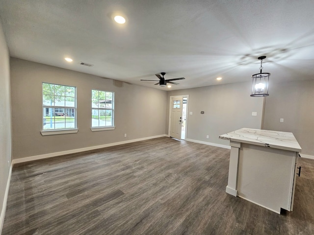 unfurnished living room featuring ceiling fan and dark wood-type flooring