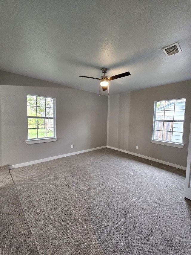 spare room with a textured ceiling, carpet floors, and ceiling fan