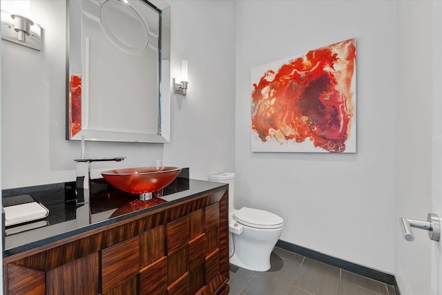 bathroom featuring baseboards, vanity, toilet, and tile patterned floors