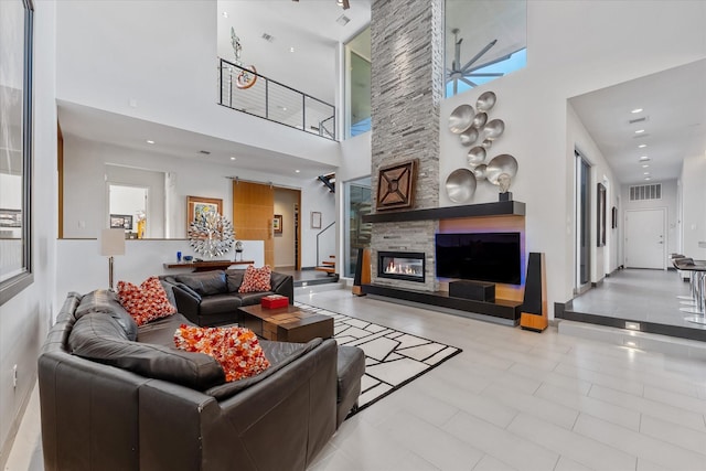 living area featuring ceiling fan, recessed lighting, a fireplace, a towering ceiling, and visible vents