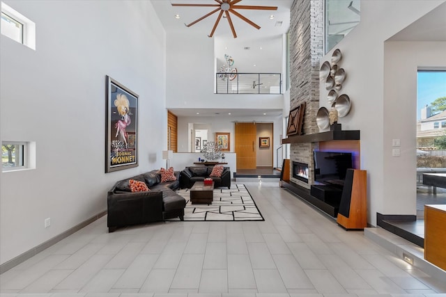 living area with baseboards, a fireplace, a high ceiling, and recessed lighting