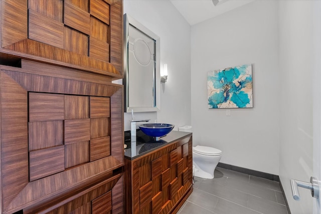 bathroom with toilet, tile patterned flooring, vanity, and baseboards