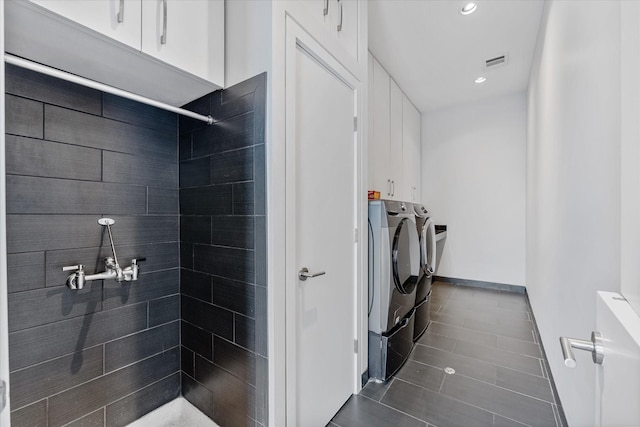 full bath featuring recessed lighting, visible vents, baseboards, washer and dryer, and a tile shower