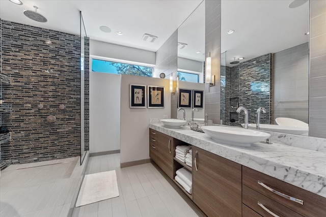 full bathroom with double vanity, visible vents, walk in shower, and a sink