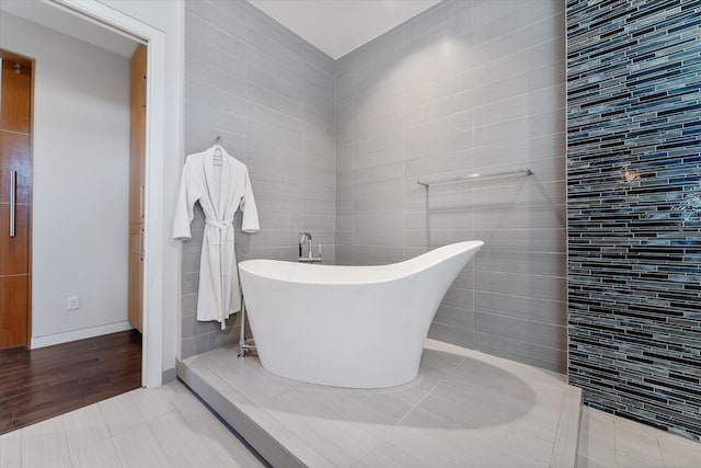 full bath with a freestanding tub, tile walls, and tile patterned floors