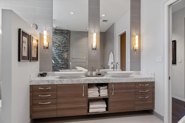 bathroom featuring double vanity, a sink, visible vents, and baseboards