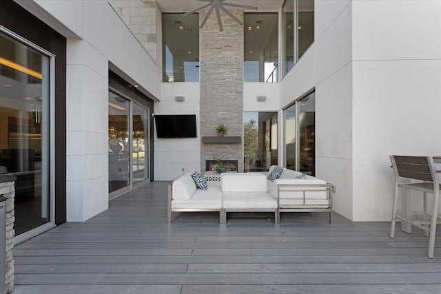 deck with ceiling fan and an outdoor living space with a fireplace