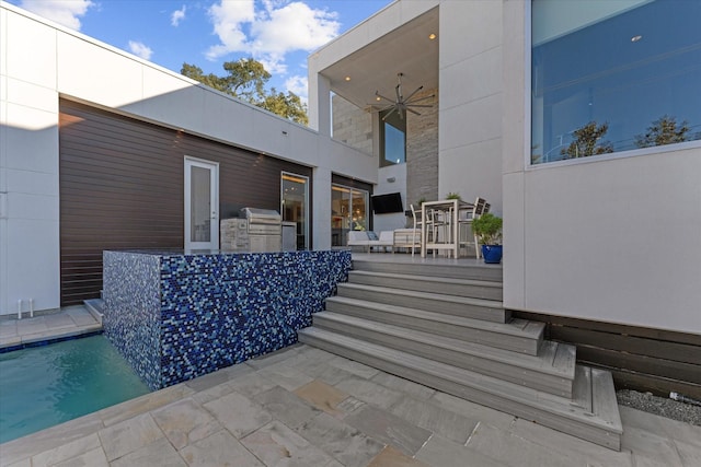 view of patio featuring exterior kitchen, a grill, an outdoor pool, and ceiling fan