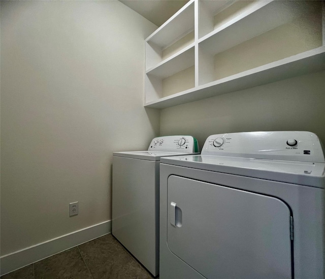 clothes washing area with washing machine and dryer and dark tile patterned floors