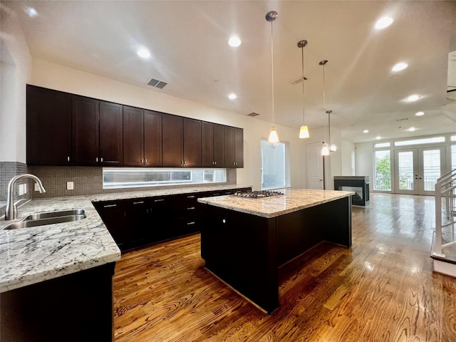 kitchen featuring pendant lighting, a center island, backsplash, french doors, and sink