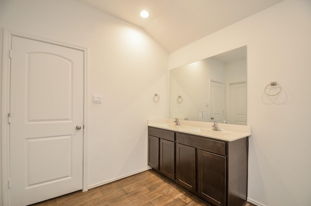 bathroom with hardwood / wood-style floors, vanity, and vaulted ceiling