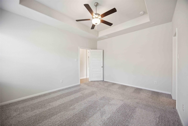 spare room with ceiling fan, a raised ceiling, and carpet floors