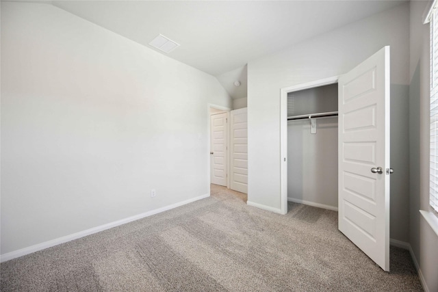 unfurnished bedroom with lofted ceiling, light carpet, and a closet