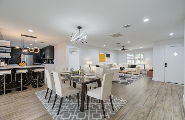 dining room with ceiling fan with notable chandelier and sink