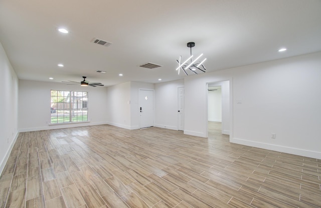 spare room with ceiling fan with notable chandelier