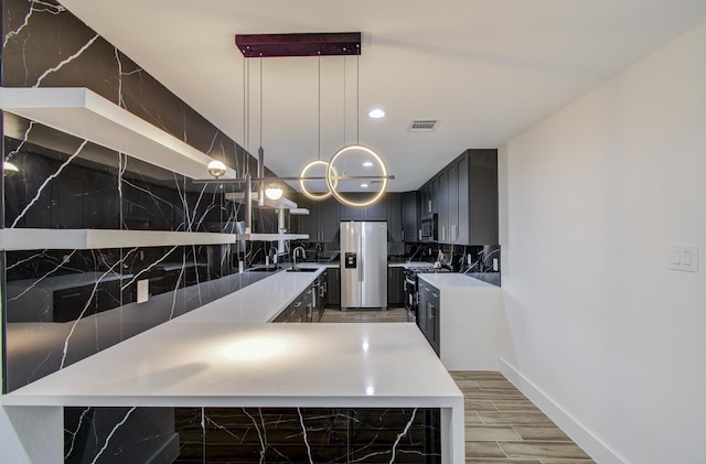 kitchen featuring sink, stainless steel appliances, hardwood / wood-style floors, pendant lighting, and decorative backsplash