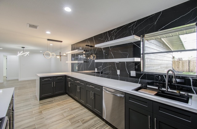 kitchen with stainless steel dishwasher, pendant lighting, kitchen peninsula, and sink