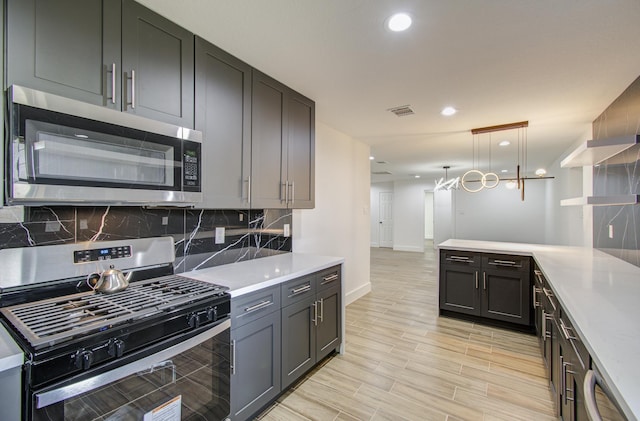 kitchen featuring tasteful backsplash, kitchen peninsula, hanging light fixtures, and appliances with stainless steel finishes