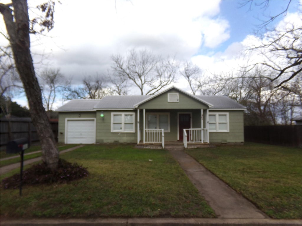 view of front of property featuring a porch, a garage, and a front yard