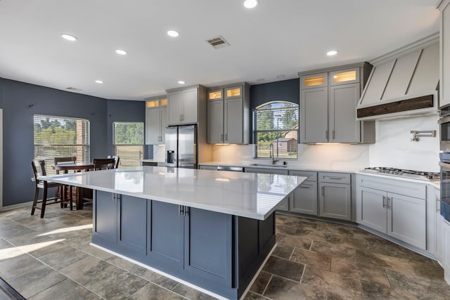 kitchen with appliances with stainless steel finishes, a center island, a wealth of natural light, and sink