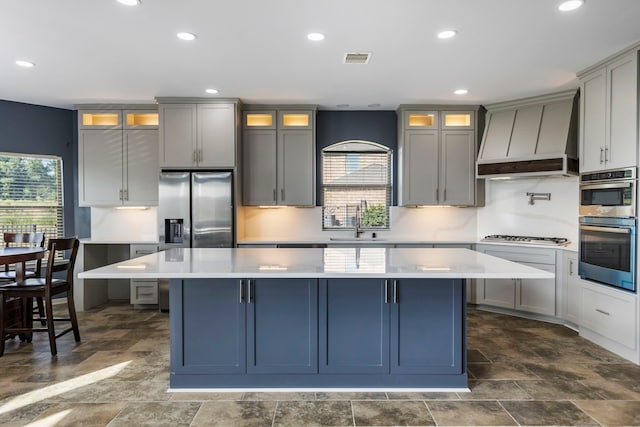 kitchen with a center island, premium range hood, sink, gray cabinets, and stainless steel appliances