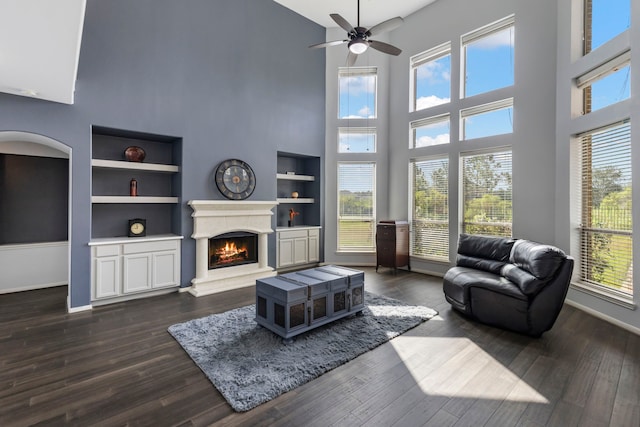 living room featuring a high ceiling, built in features, and dark wood-type flooring