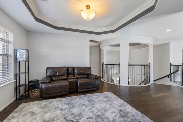 living room featuring ornamental molding, dark wood-type flooring, and a tray ceiling