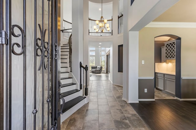 foyer entrance featuring dark wood-type flooring, a chandelier, and ornamental molding