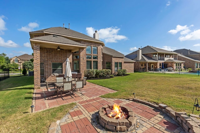 rear view of property with a lawn, ceiling fan, a patio, and an outdoor fire pit