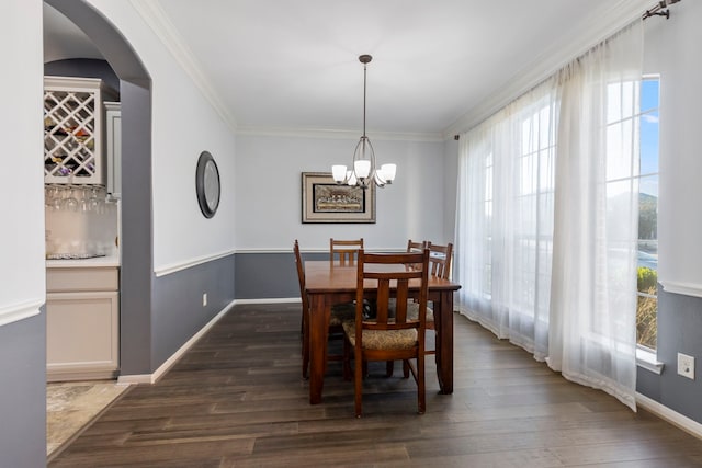 dining area with dark hardwood / wood-style flooring, a wealth of natural light, crown molding, and a notable chandelier