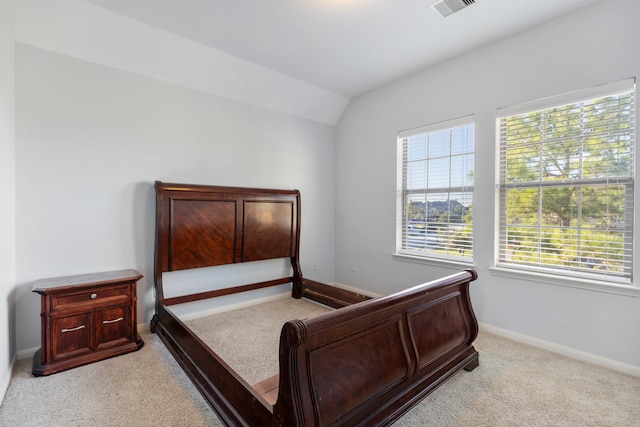 bedroom featuring light colored carpet and lofted ceiling